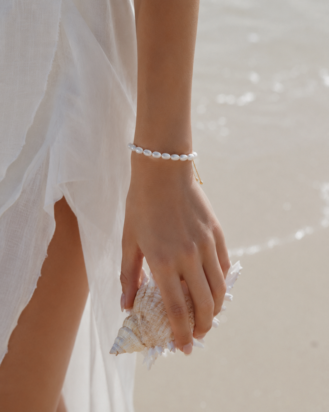 Armband Alba met parels om de pols van een model met een schelp