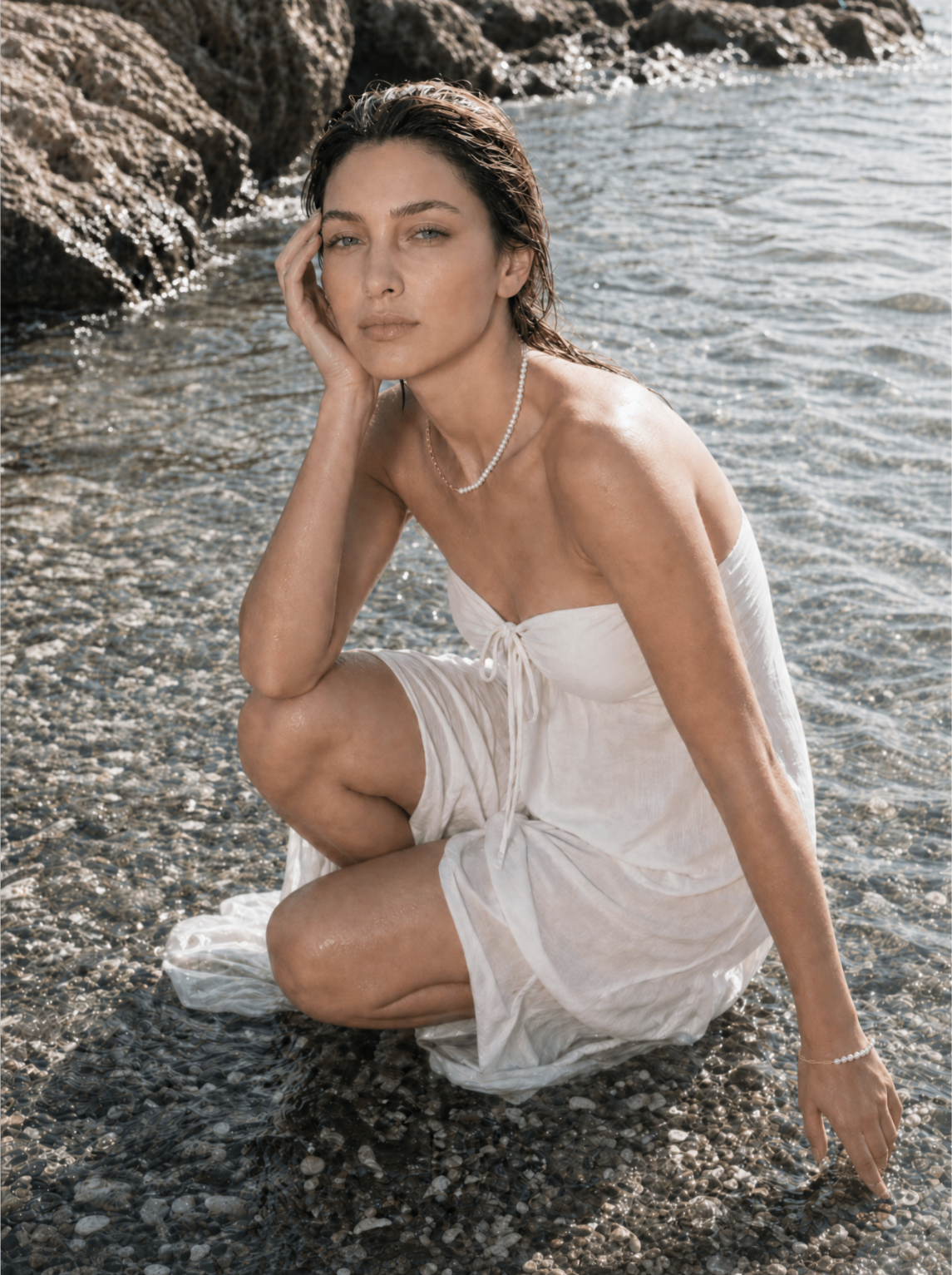 Gouden ketting Aurelia met parels door een model gedragen aan zee