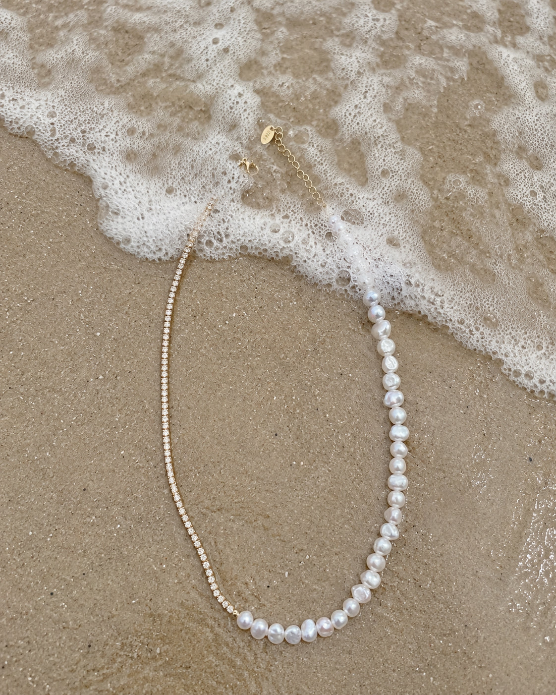 Gouden ketting Evia met parels gelegd op het zand
