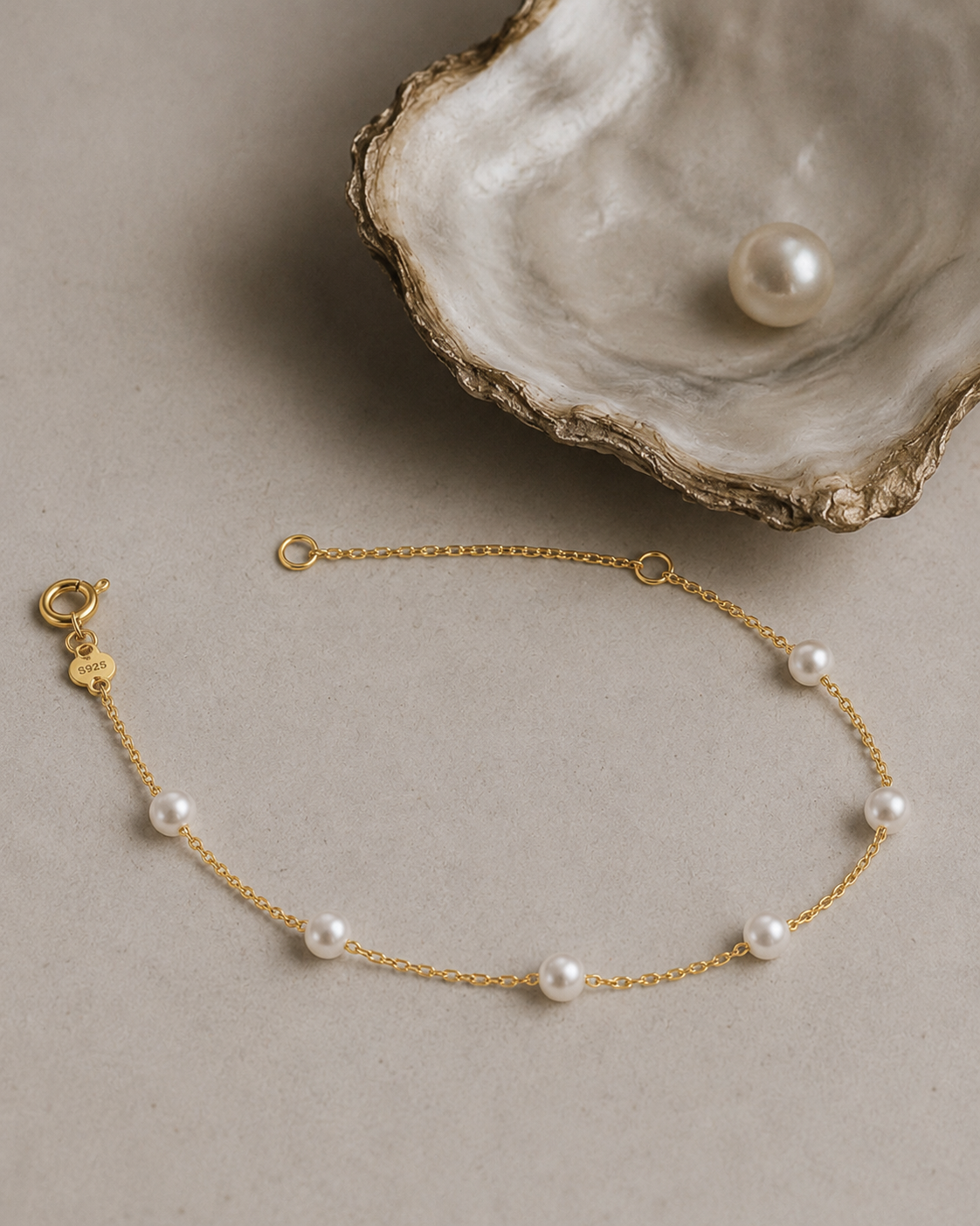 Gouden armband Adria met parels gelegd naast een schelp
