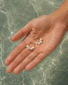 Gouden oorbellen Adria met parels vastgehouden in een hand in het water