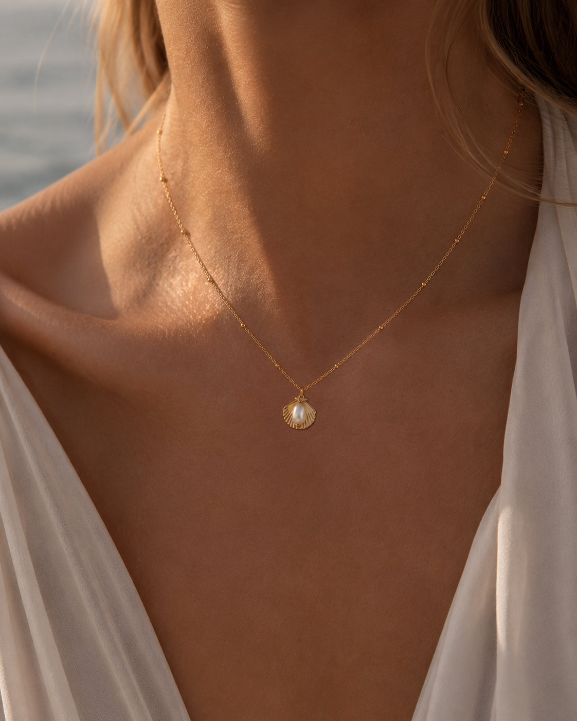 Gouden ketting Cala met een schelpbedel en parel in de hals