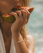 Podwójna bransoletka Selene z perłami na modelce trzymającej papaję