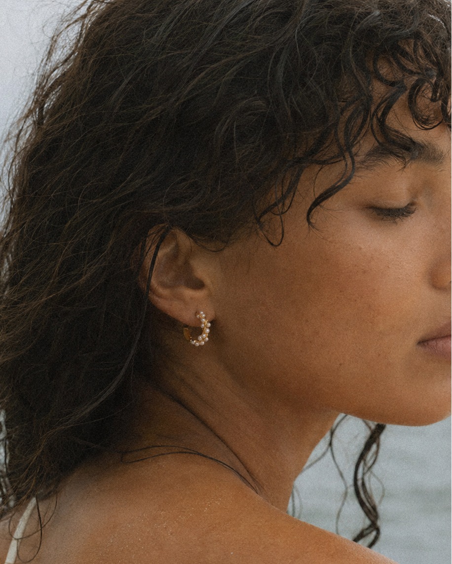 Gouden hoepeloorbel Serena met parels – close-up in een oor